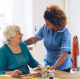 caregiver preparign a lunch to a senior woman