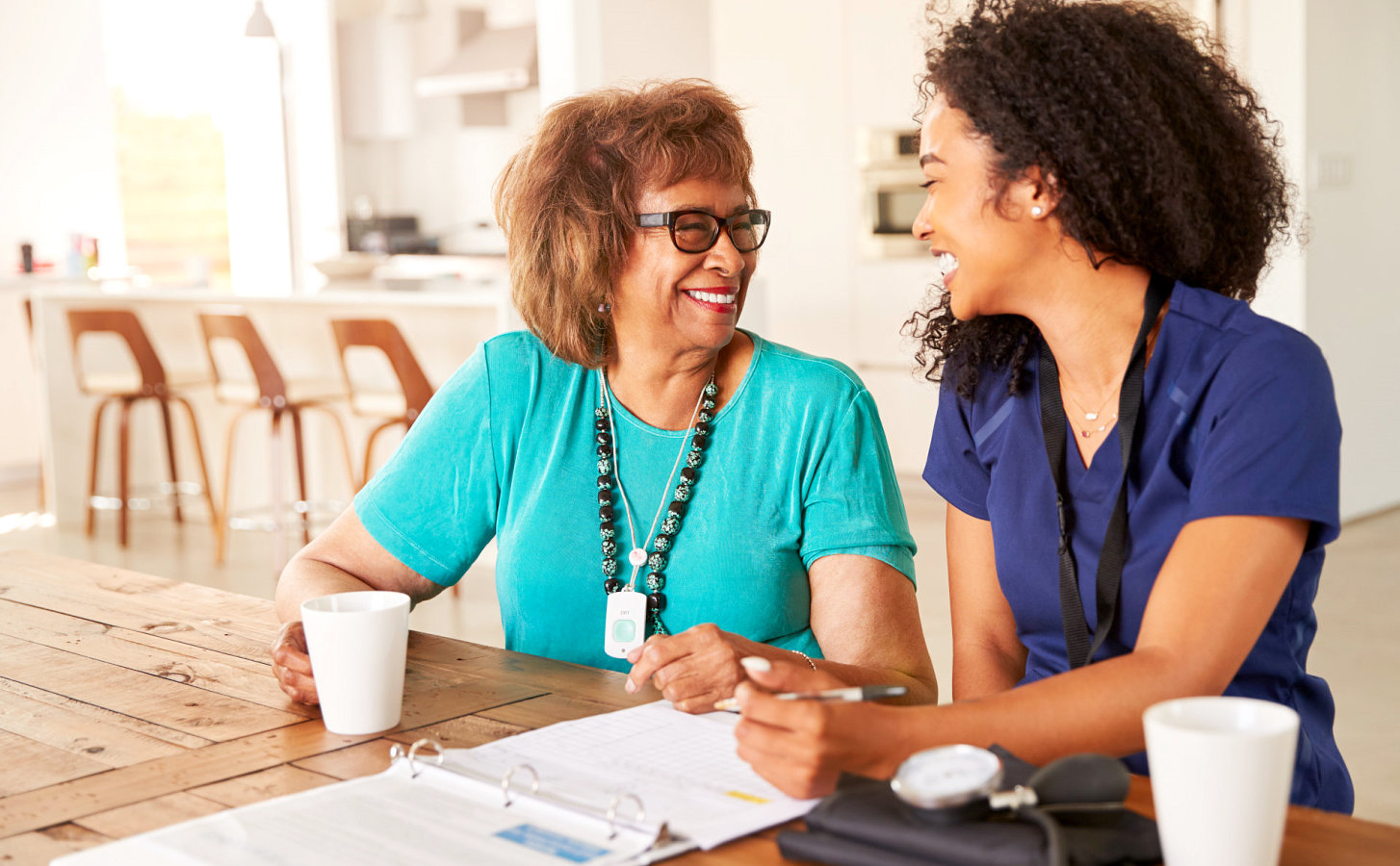 caregiver and a senior woman happily writing on a pad