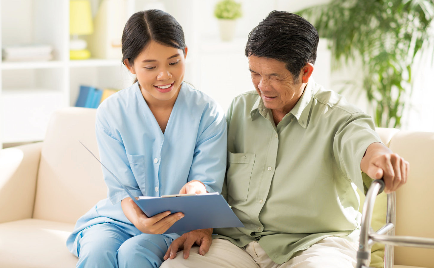 caregiver and a senior man looking at a pad