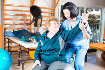 senior patient doing an exercise  while assisted by a caregiver