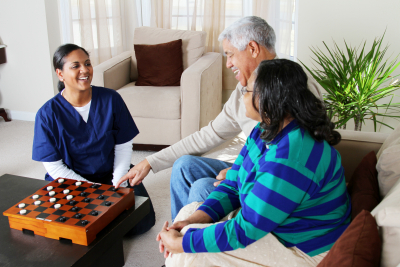 two senior couple playing game with their caregiver