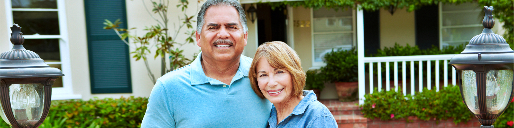 senior couple smiling in front of a house